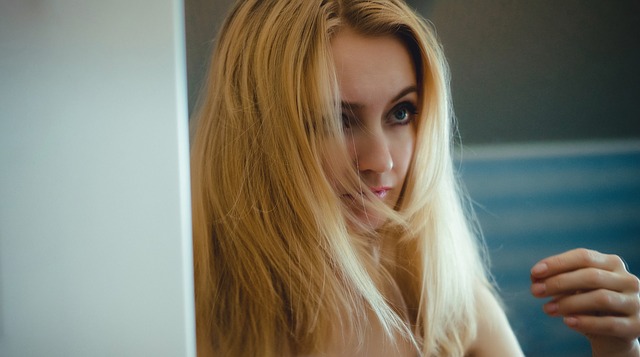 A blonde woman with unkept hair staring at something or someone.